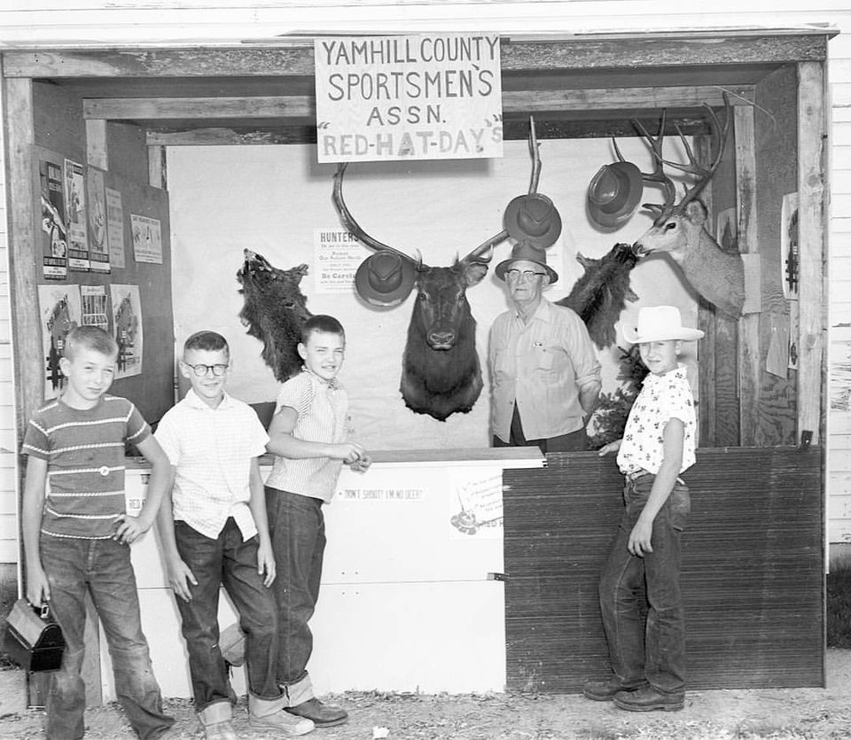 Historic photo of four boys standing in front of hunters booth.